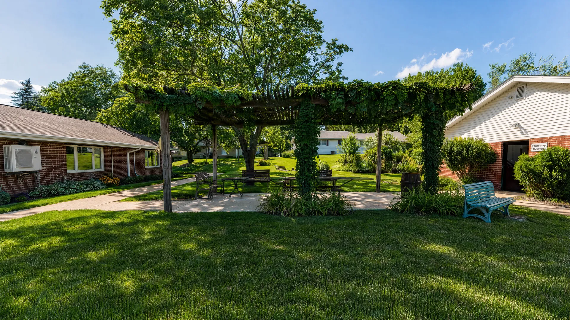 Courtyard with a vine-covered pergola and benches at Rehabilitation Center of Independence
